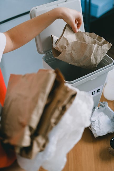 Close-up view of a tightly tied black plastic rubbish bag with a crinkled texture, placed against a plain, light-colored wall, suggesting indoor or outdoor waste collection activity. The bag appears full and is situated in the foreground, with additional bags partially visible behind it, indicating a collection of household waste or refuse awaiting removal. The environment seems clean and free of clutter, with no other objects or environmental details visible. The focus on the black trash bag aligns with private rubbish disposal services such as those offered by Rubbish Removal Lambeth, highlighting materials typically handled during on-site clearance or alternative waste handling efforts. The neutral lighting emphasizes the shiny, reflective surface of the plastic, providing a clear and neutral visual suitable for accessibility and SEO relevance related to rubbish collection and waste management.